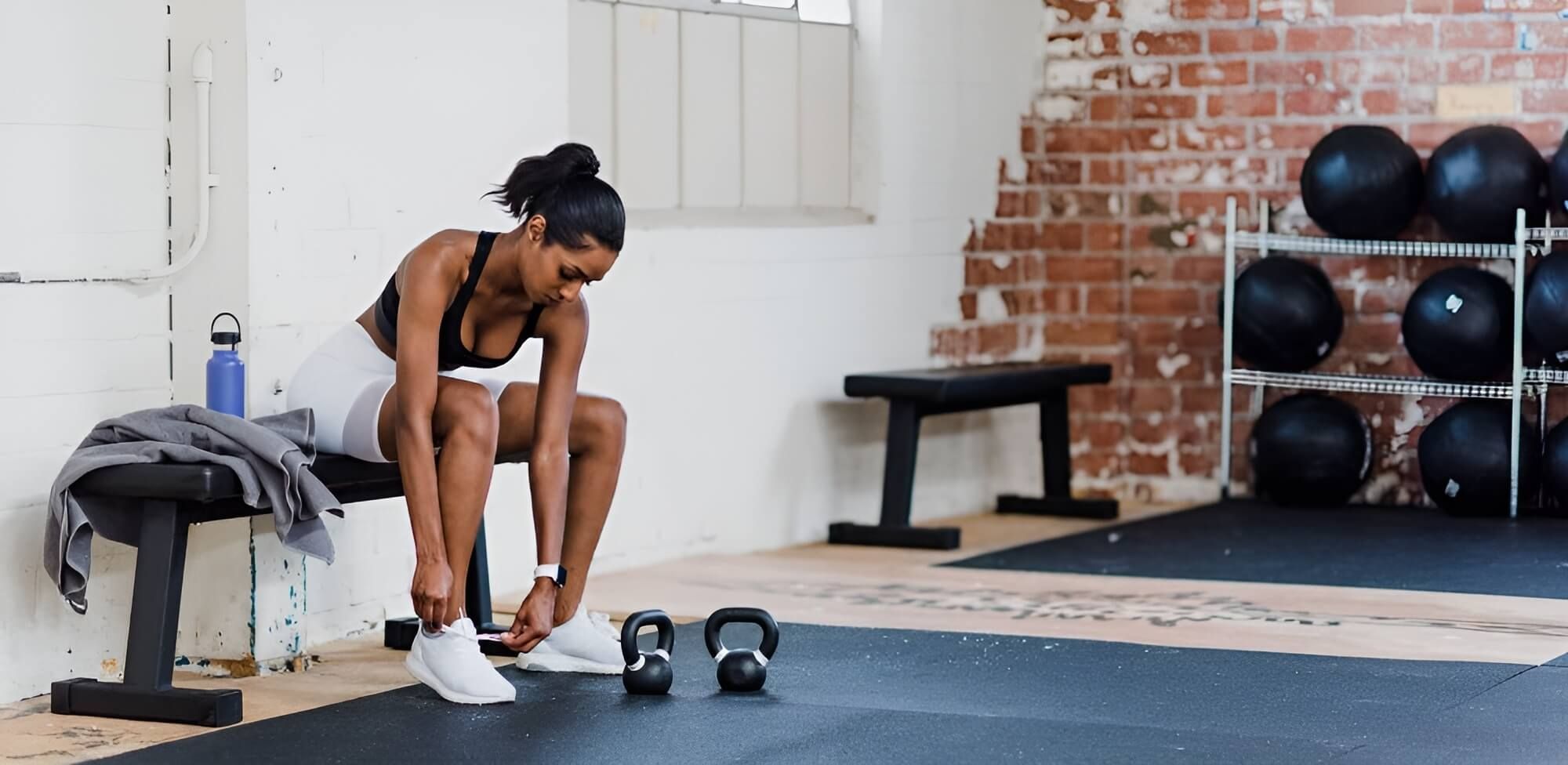 Frau bindet sich die Schuhe in einem Fitnessstudio